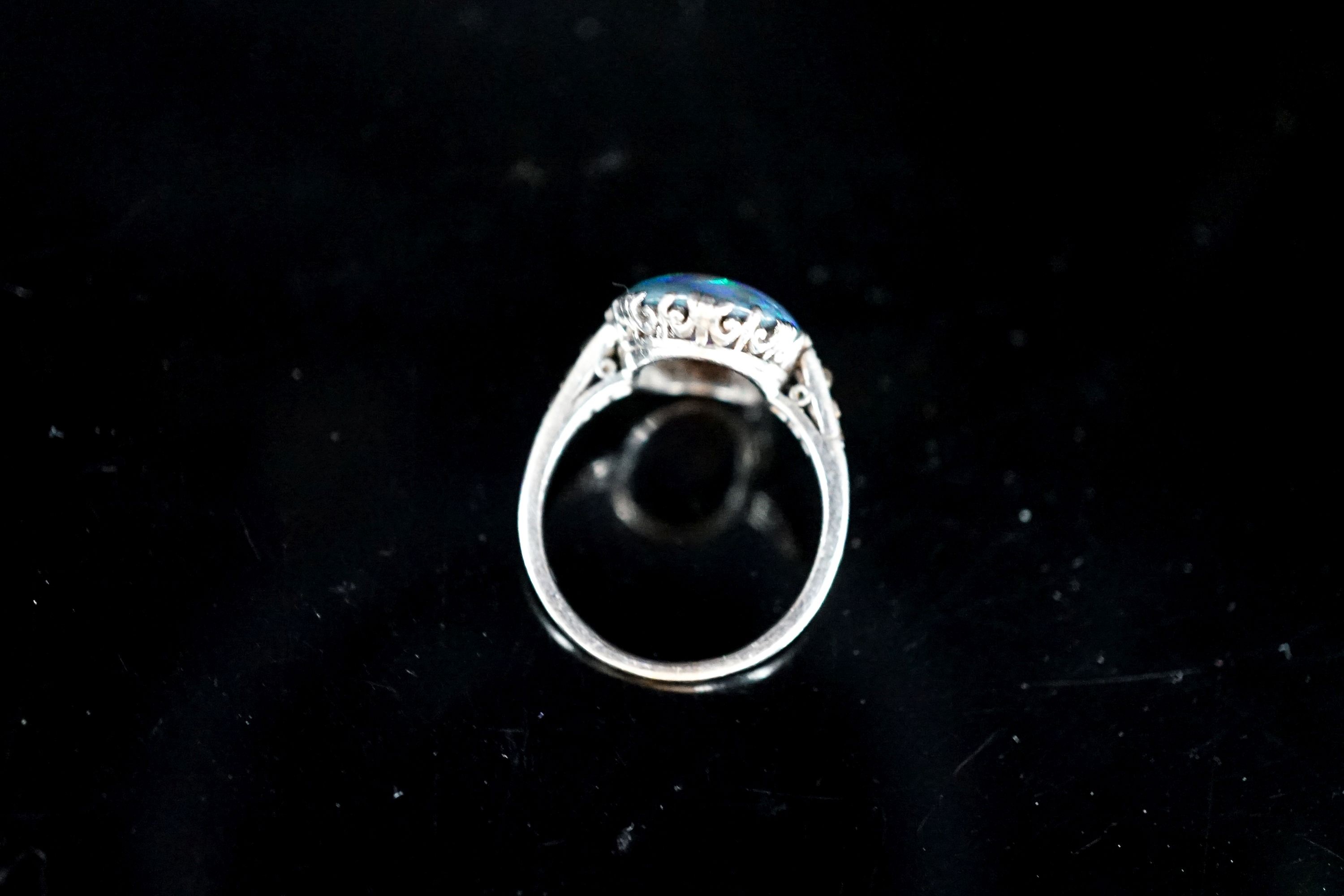 A 1920's white metal and black opal set oval dress rig, with diamond set shoulders, size N, gross 3.8 grams.